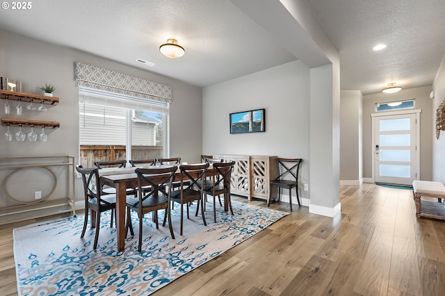 dining room with visible vents, a textured ceiling, baseboards, and wood finished floors