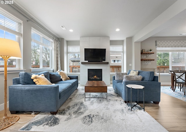 living room with visible vents, a tile fireplace, light wood-style flooring, and recessed lighting