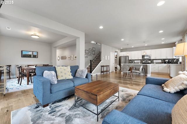 living room with baseboards, stairway, light wood-type flooring, and recessed lighting