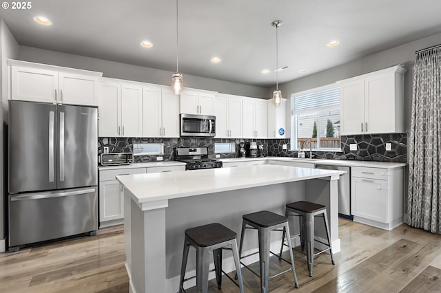 kitchen with stainless steel appliances, white cabinets, light countertops, and a kitchen island