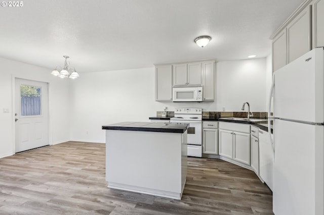 kitchen with white appliances, white cabinets, sink, hanging light fixtures, and a chandelier