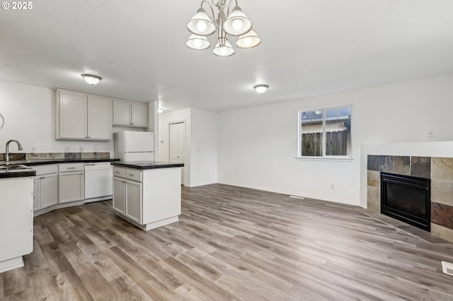 kitchen featuring hanging light fixtures, light hardwood / wood-style floors, a fireplace, white appliances, and an inviting chandelier