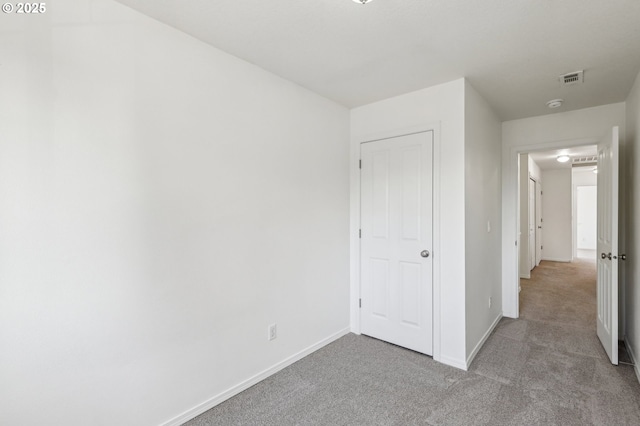 unfurnished bedroom featuring light colored carpet and a closet