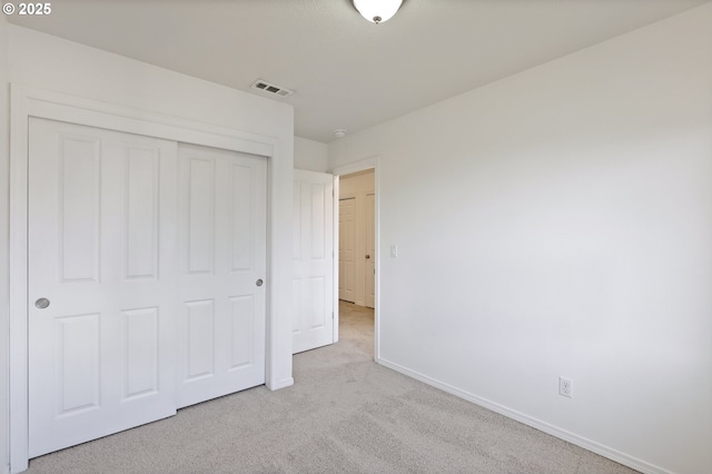 unfurnished bedroom featuring light colored carpet and a closet