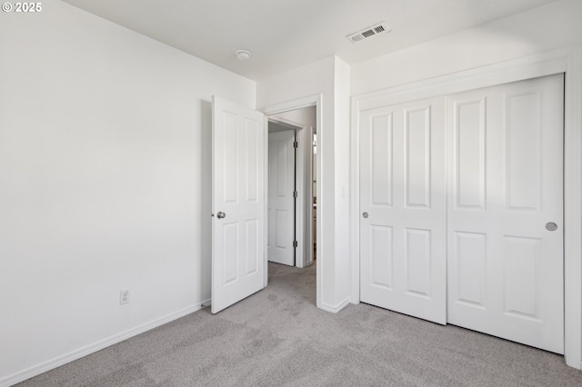 unfurnished bedroom with light carpet and a closet