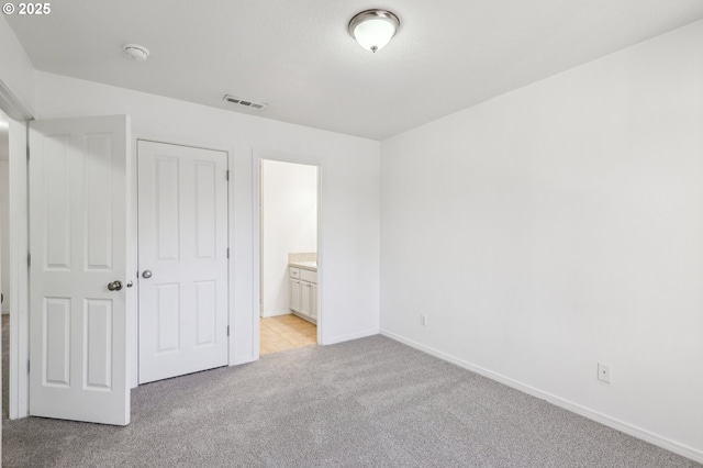 unfurnished bedroom featuring light carpet, a closet, and connected bathroom