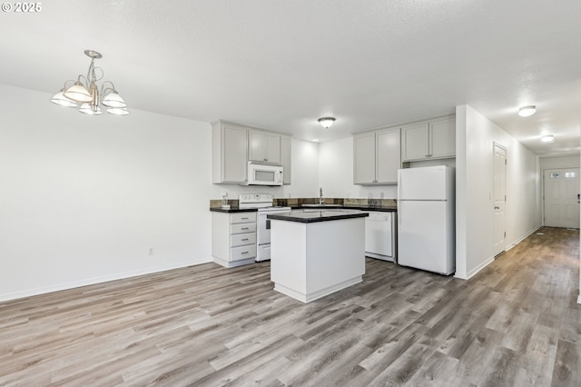 kitchen featuring white appliances, light hardwood / wood-style floors, a chandelier, sink, and decorative light fixtures