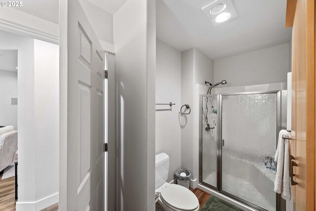bathroom featuring a stall shower, toilet, and wood finished floors