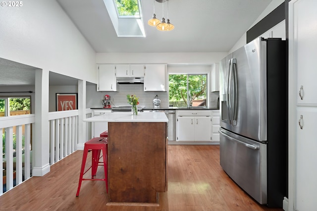7225 SW Anne St, Beaverton, OR 97008 - kitchen with appliances with stainless steel finishes, under cabinet range hood, a skylight, white cabinetry, and lofted ceiling
