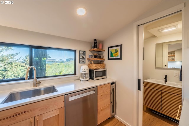 kitchen featuring light brown cabinets, a sink, light wood-style flooring, light countertops, and appliances with stainless steel finishes