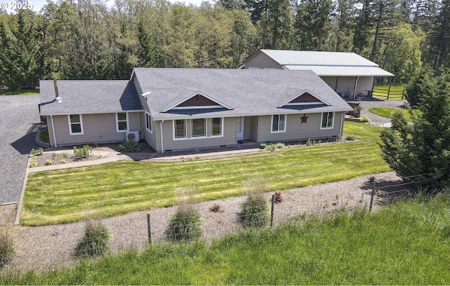 ranch-style home with a shingled roof and a front yard