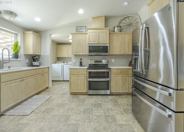 kitchen featuring washer and clothes dryer, appliances with stainless steel finishes, and light brown cabinetry
