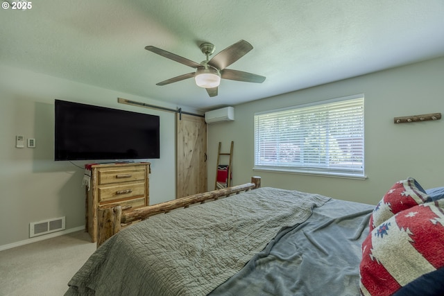 bedroom featuring a ceiling fan, visible vents, a barn door, a wall mounted air conditioner, and carpet floors
