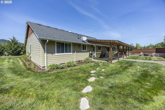view of front of house with a patio, a shingled roof, a front lawn, and fence
