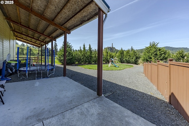 view of patio / terrace featuring a trampoline, a playground, and fence
