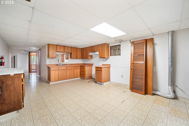1339 SW 27th Ct, Gresham, OR 97080 - kitchen featuring a paneled ceiling, baseboards, light countertops, brown cabinetry, and under cabinet range hood