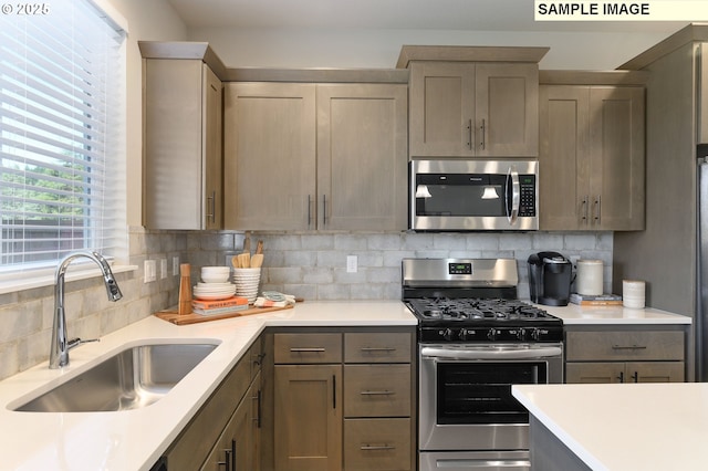 kitchen featuring stainless steel appliances, a sink, light countertops, and decorative backsplash