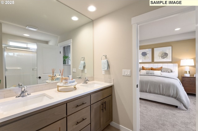 ensuite bathroom featuring double vanity, recessed lighting, a shower with door, and baseboards