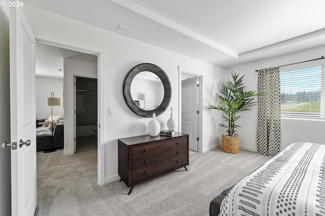 bedroom with visible vents, light carpet, a textured ceiling, and baseboards