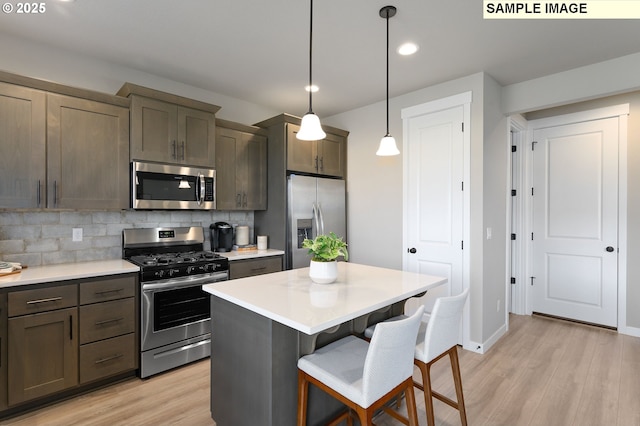 kitchen featuring stainless steel appliances, light wood-style floors, tasteful backsplash, light countertops, and a breakfast bar