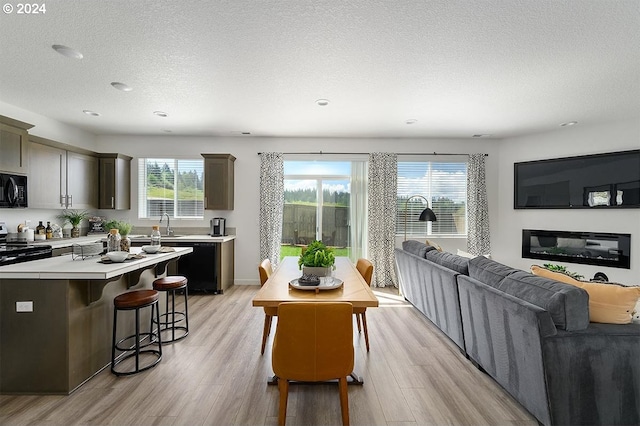 kitchen featuring a breakfast bar, light countertops, open floor plan, light wood-type flooring, and black appliances