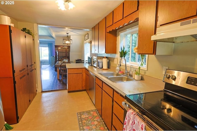 929 S 7th St, Coos Bay, OR 97420 - kitchen featuring appliances with stainless steel finishes, a sink, brown cabinets, under cabinet range hood, and healthy amount of natural light