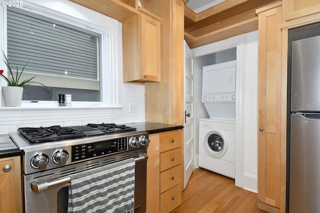 1330 SE 14th Ave SE, Portland, OR 97214 - kitchen featuring appliances with stainless steel finishes, stacked washer / dryer, dark countertops, light wood-type flooring, and light brown cabinetry