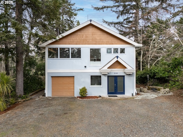 view of front of property with stucco siding, an attached garage, driveway, and french doors