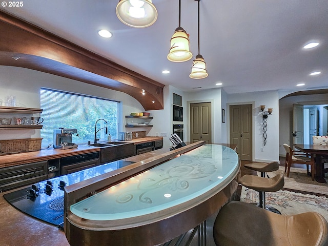 kitchen featuring open shelves, decorative light fixtures, a sink, black microwave, and stainless steel oven