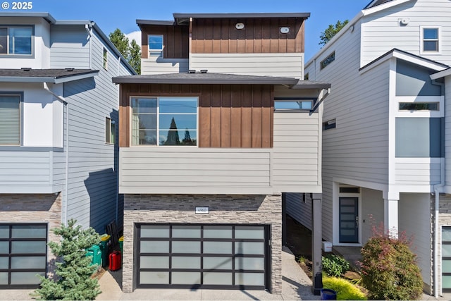 contemporary home with a garage, stone siding, and board and batten siding