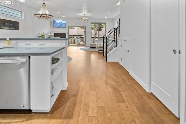 kitchen featuring dark countertops, light wood-style flooring, an inviting chandelier, open shelves, and stainless steel dishwasher