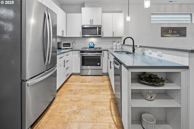 kitchen with appliances with stainless steel finishes, dark countertops, a sink, and open shelves