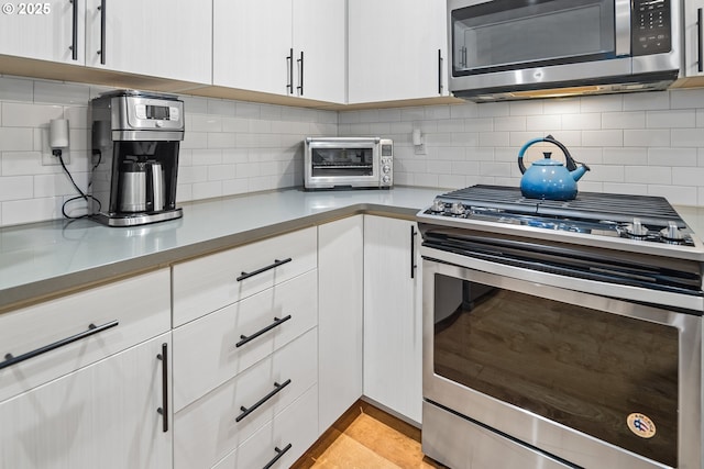 kitchen featuring tasteful backsplash, a toaster, white cabinetry, and stainless steel appliances