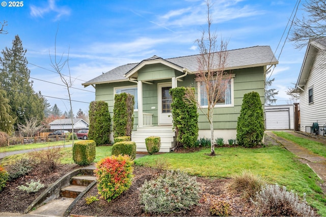 bungalow-style home featuring a garage, an outdoor structure, a shingled roof, and a front lawn