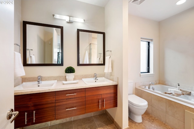 bathroom featuring tiled tub, vanity, tile patterned floors, and toilet