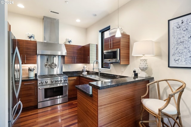 kitchen with sink, appliances with stainless steel finishes, range hood, decorative light fixtures, and kitchen peninsula