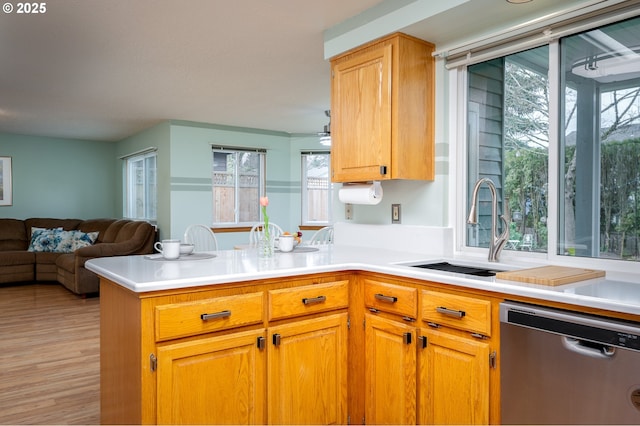 kitchen with sink, stainless steel dishwasher, light wood-type flooring, and kitchen peninsula