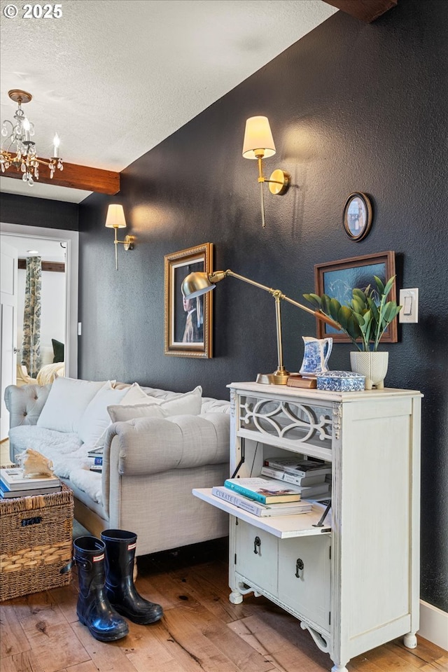 bedroom featuring beamed ceiling, wood-type flooring, and an inviting chandelier