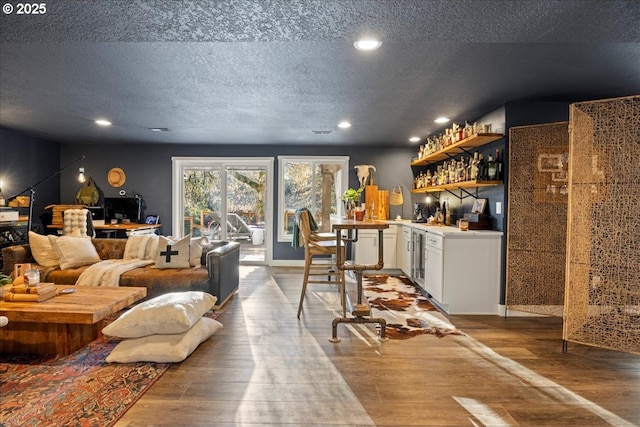 bar with wood-type flooring, white cabinetry, and a textured ceiling