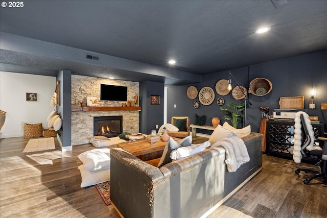 living room featuring a stone fireplace and wood-type flooring