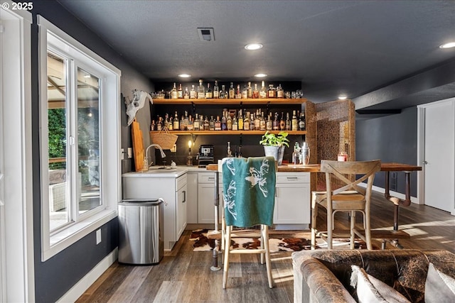 bar featuring white cabinets, sink, and dark wood-type flooring