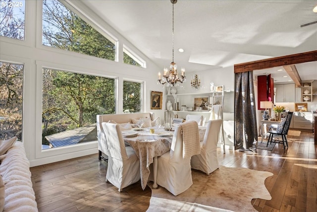 dining space with high vaulted ceiling, wood-type flooring, and a notable chandelier