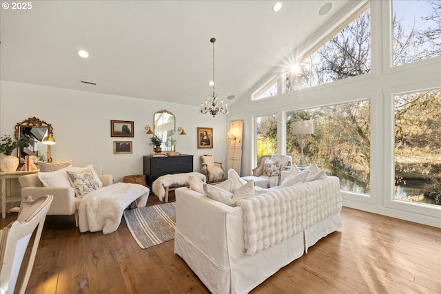 living room featuring wood-type flooring, high vaulted ceiling, and a notable chandelier