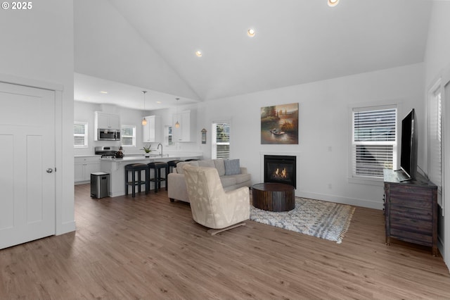 5769 NW Logan Rd, Lincoln City, OR 97367 - living area with light wood-style flooring, a glass covered fireplace, recessed lighting, healthy amount of natural light, and high vaulted ceiling