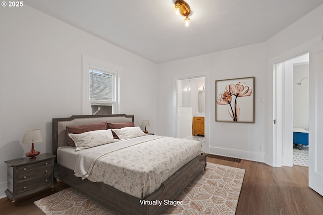 bedroom featuring wood finished floors, baseboards, and ensuite bath