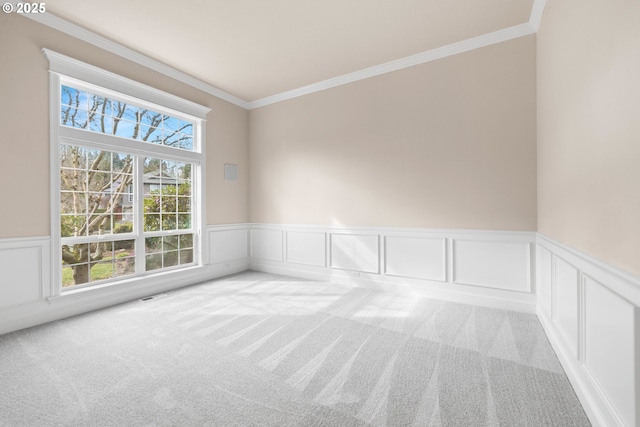 unfurnished room with a wainscoted wall, carpet, and crown molding