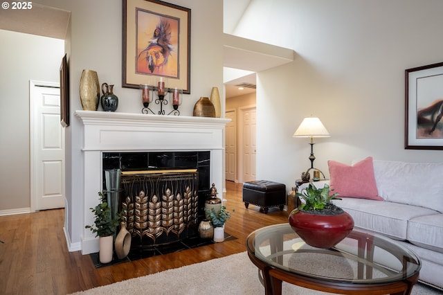 living room featuring a fireplace with flush hearth, wood finished floors, and baseboards