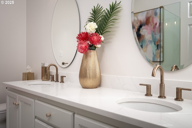 bathroom featuring a sink, toilet, and double vanity