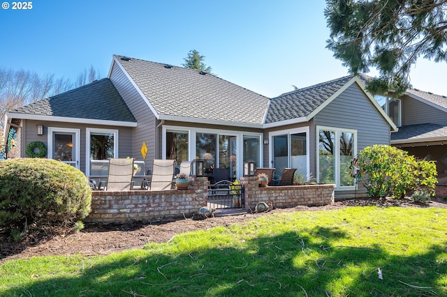 back of property featuring a patio, a shingled roof, and a lawn