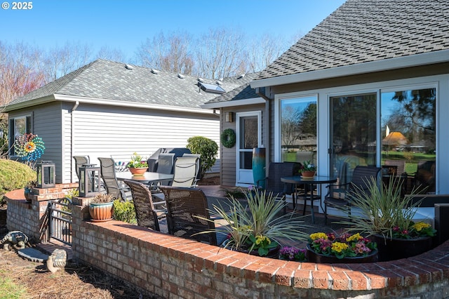 rear view of property featuring a shingled roof and a patio